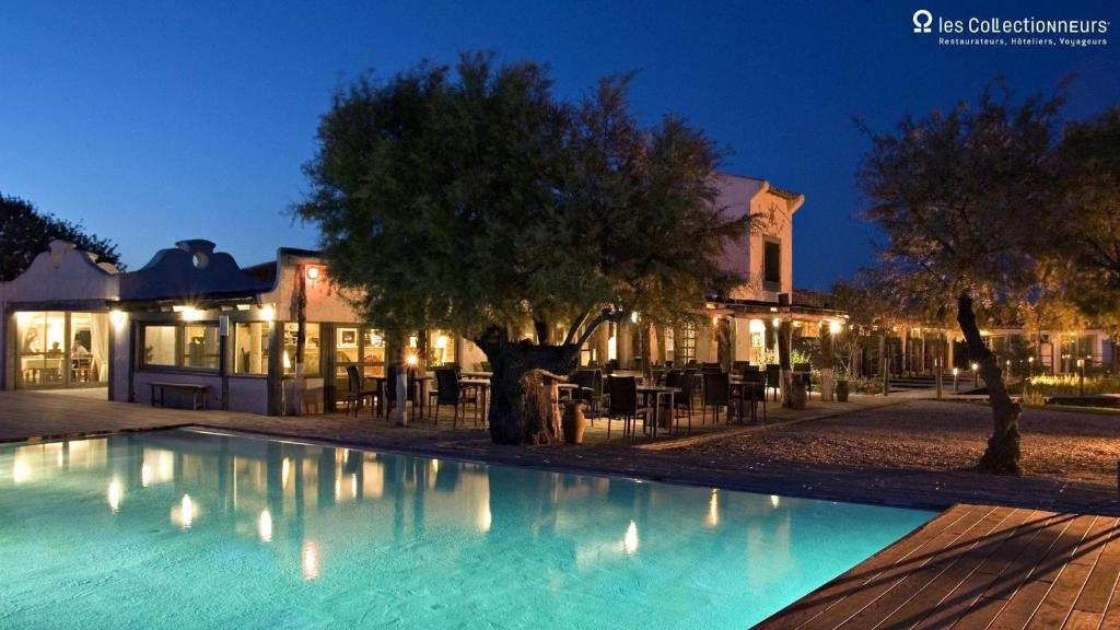 una piscina di fronte a un edificio di notte di Hôtel Restaurant Les Arnelles a Saintes-Maries-de-la-Mer