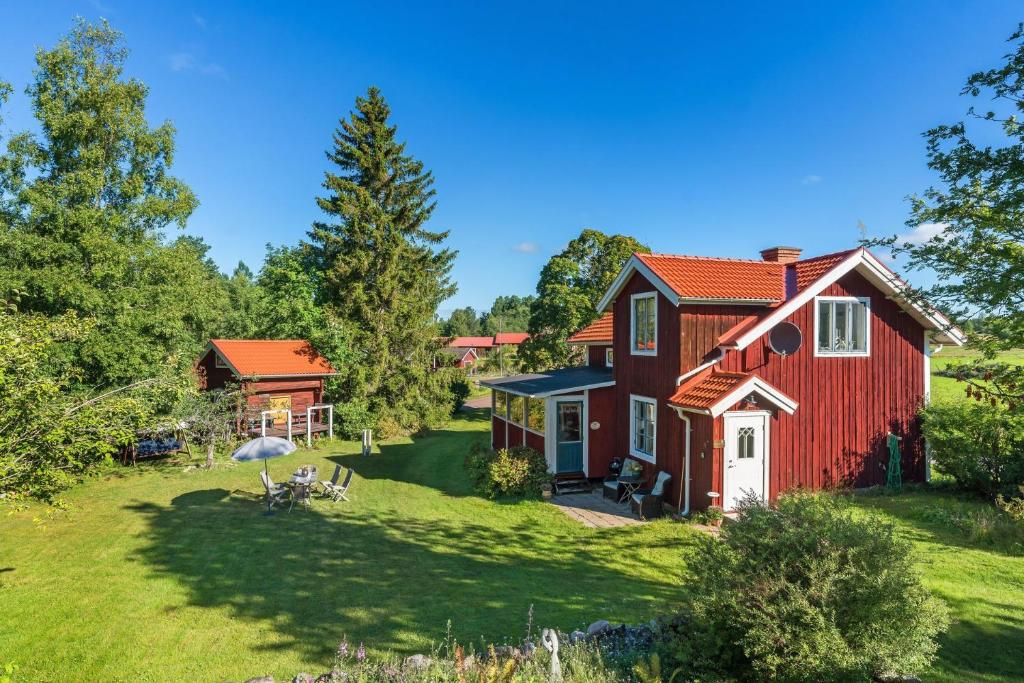 una casa roja en un patio verde con una casa en Charming cottage outside Rattvik, en Vikarbyn