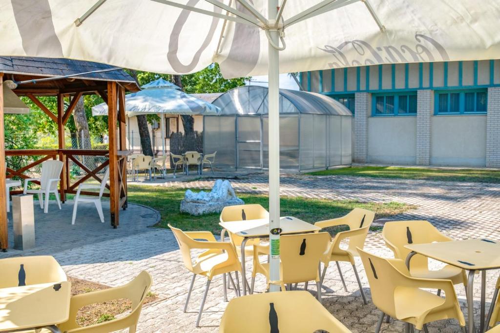 patio ze stołami i krzesłami pod parasolem w obiekcie Zsóry Liget Vendégház w Mezőkövesd