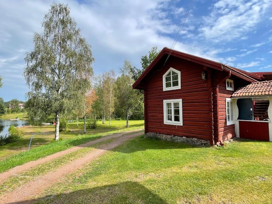 una pequeña casa roja con un camino de tierra delante de ella en Dalastuga med tillgång till badplats en Leksand