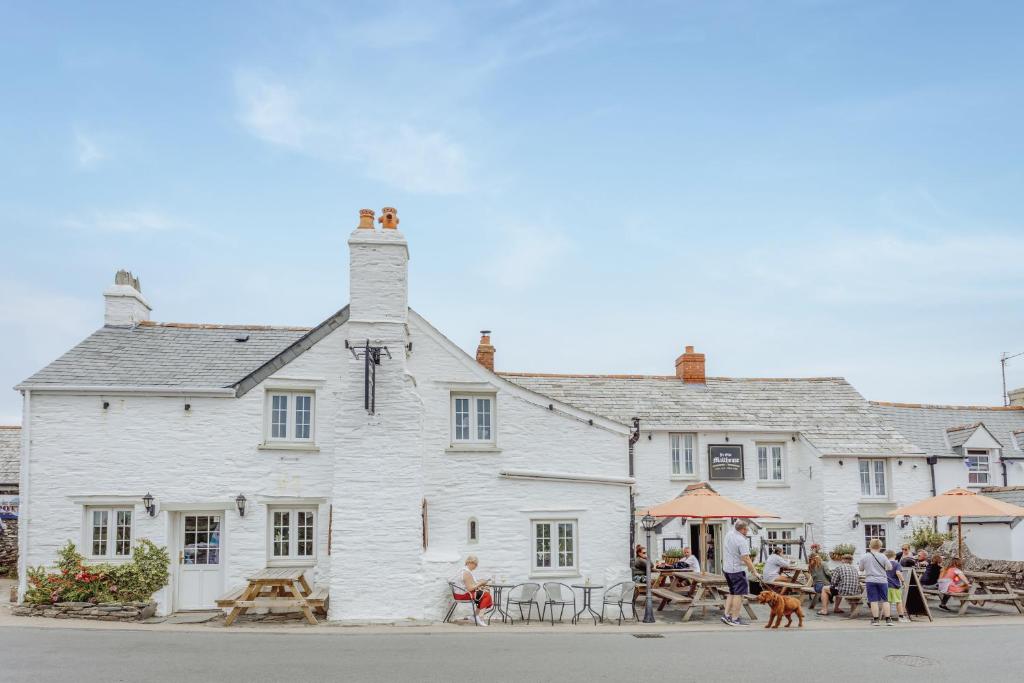 a white building with people sitting outside of it at The Olde Malthouse Inn in Tintagel