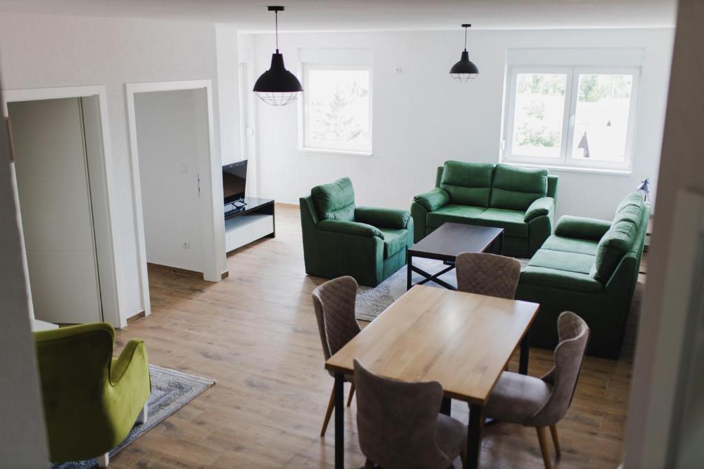 Class Apartment في برتشكو: غرفة معيشة مع كراسي خضراء وطاولة