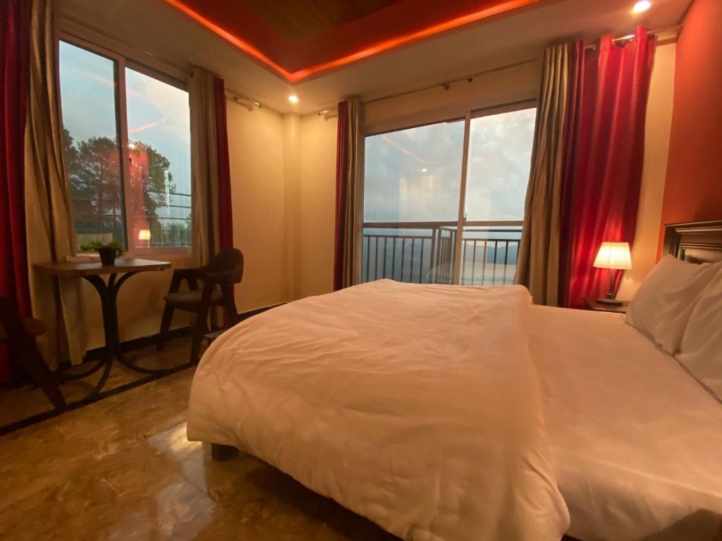 sypialnia z dużym białym łóżkiem i oknem w obiekcie AK Hotel & Suites w mieście Murree