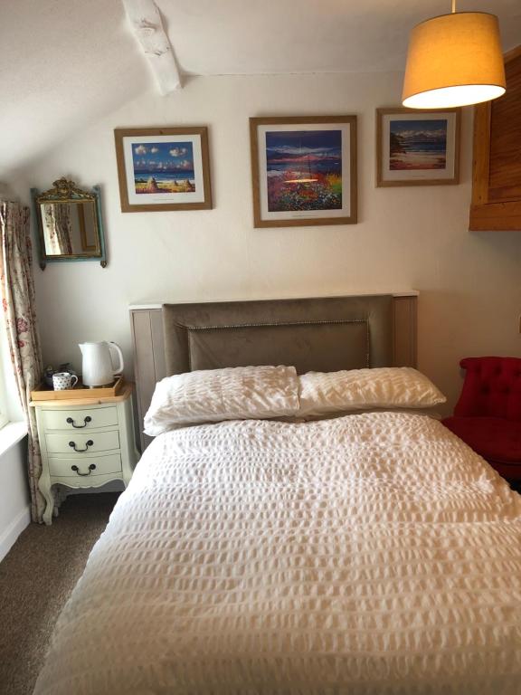 a bedroom with a bed with a white comforter at 1 Laurel Cottages in Dawlish