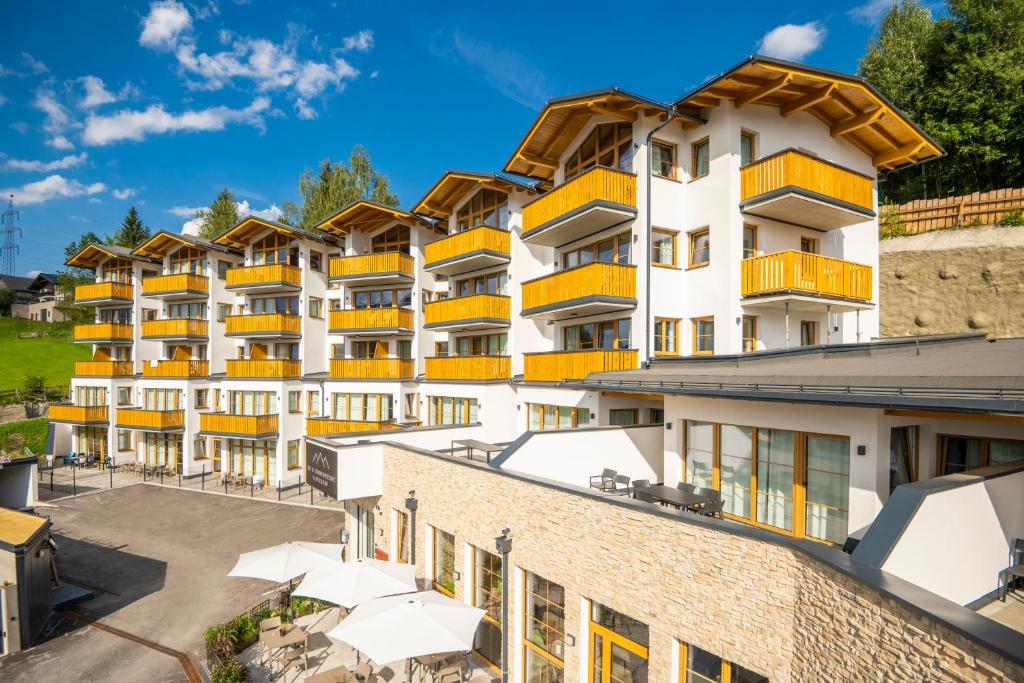 an apartment building with orange balconies and a parking lot at Ski- & Sonnenresort Alpendorf by AlpenTravel in Sankt Johann im Pongau