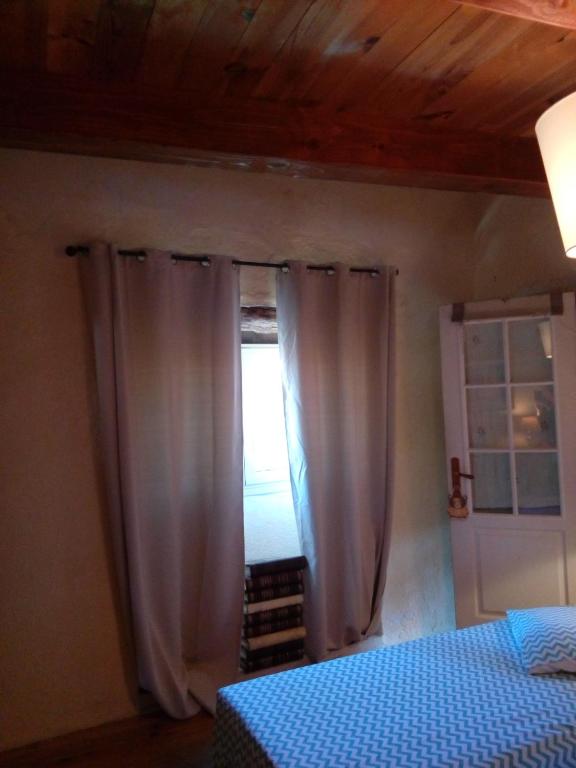 a bedroom with a bed and a window with curtains at Comfortable Quiet House in the countryside Porte-du-Quercy for 8 people in Sérignac
