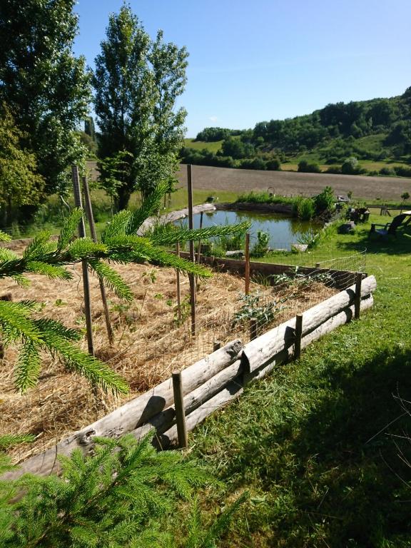 a garden with a wooden fence and a pond at Comfortable Quiet House in the countryside Porte-du-Quercy for 8 people in Sérignac