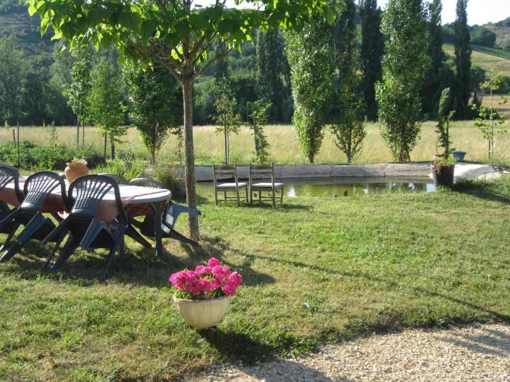 a table and chairs in a yard with flowers in a pot at Comfortable Quiet House in the countryside Porte-du-Quercy for 8 people in Sérignac