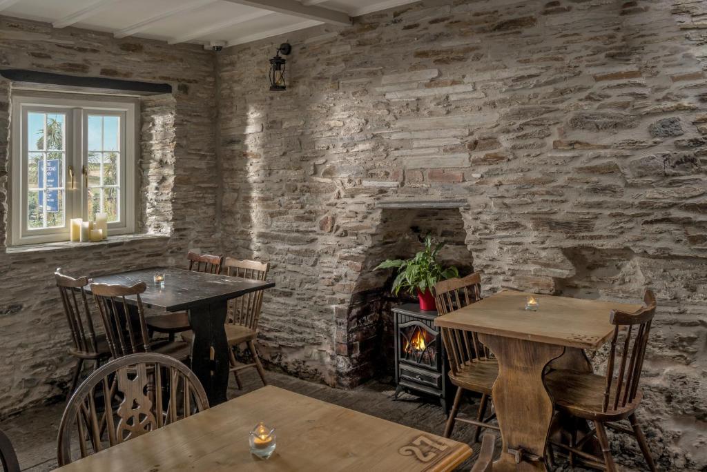 a restaurant with two tables and a stone wall at The Olde Malthouse Inn in Tintagel