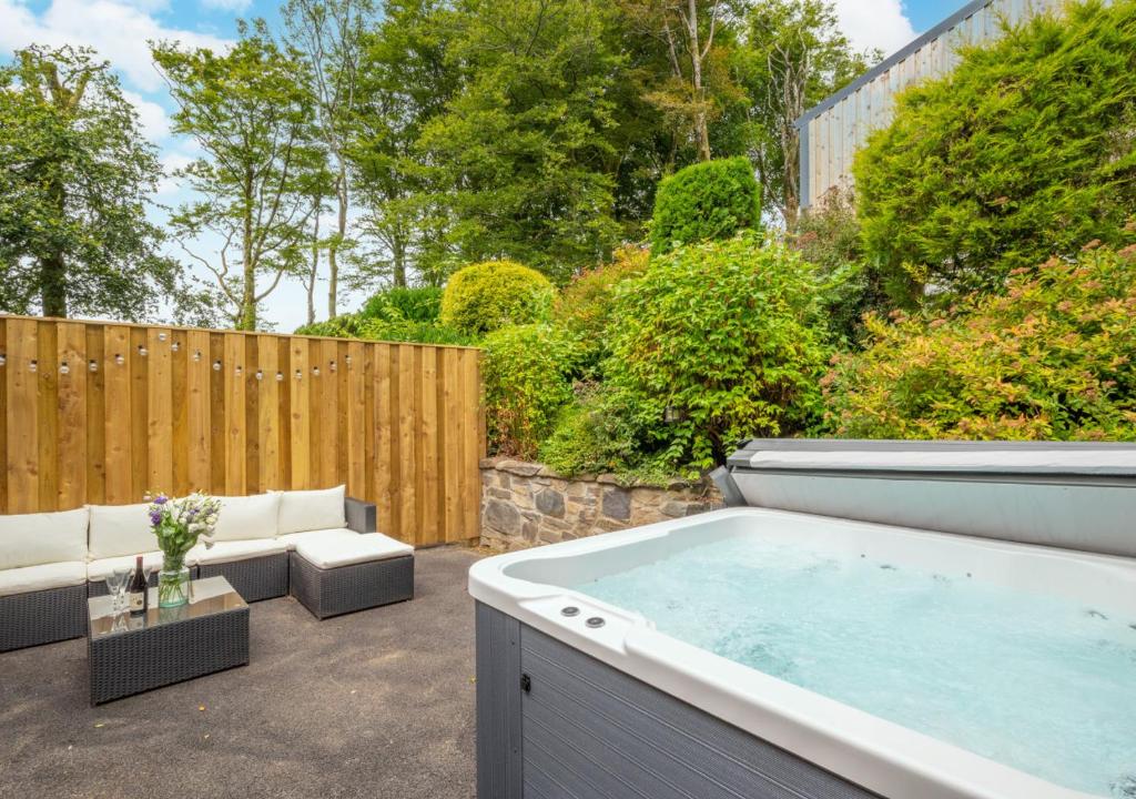 a hot tub in a backyard with a fence at Hafod y Llwynog in Cross Inn