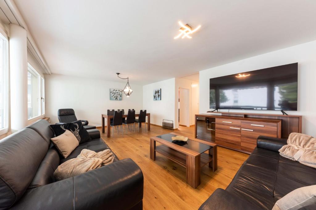 ein Wohnzimmer mit einem Sofa und einem Flachbild-TV in der Unterkunft Joe's Apartment am Bolgen in Davos