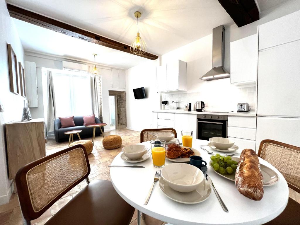 un comedor con una mesa blanca con comida. en La Duchesse - Grand Appartement Au Coeur de Dijon, en Dijon