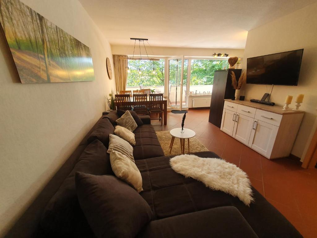 un gran sofá marrón en una sala de estar con TV en Ferienwohnung Naturseelen mit Schwimmbad und Sauna, en Braunlage