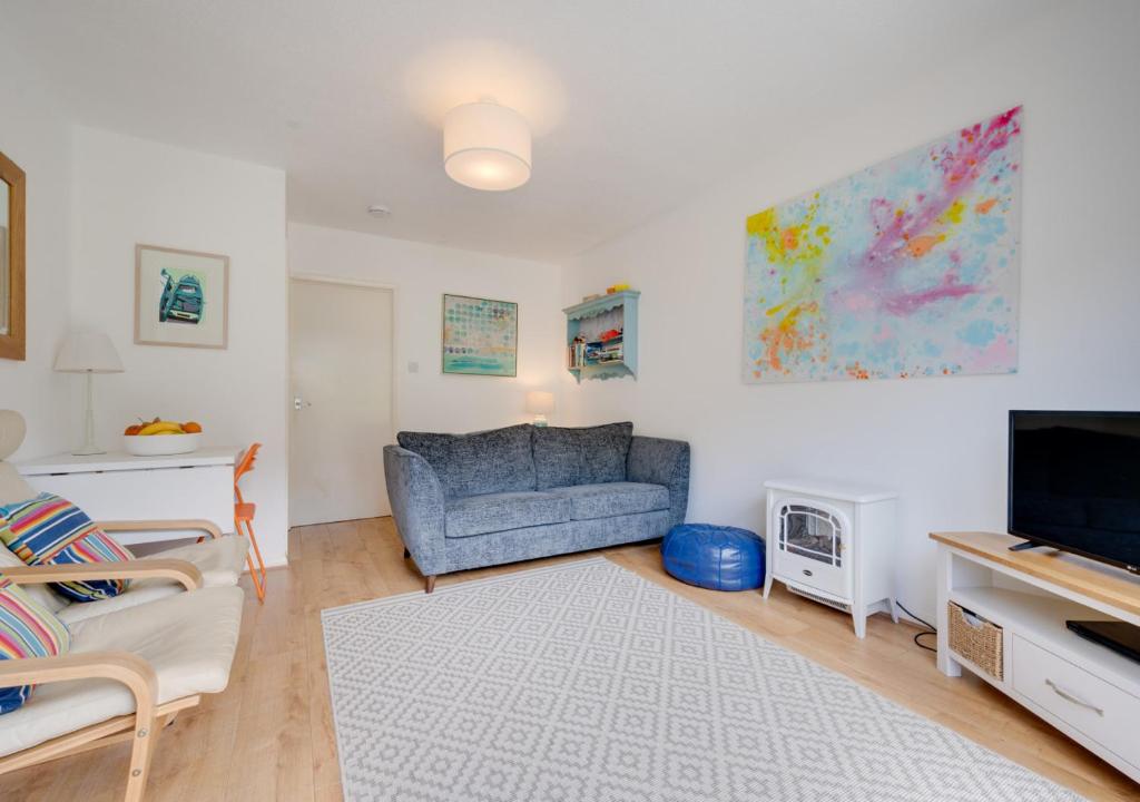 een woonkamer met een blauwe bank en een tv bij Bayview Bungalow 365 in Oxwich