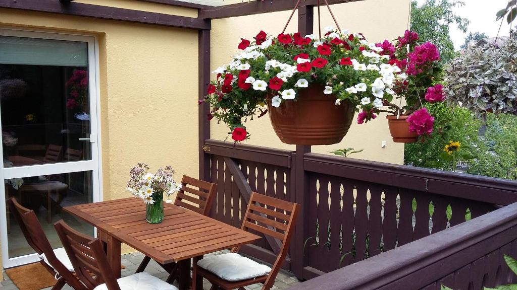 a wooden table and chairs on a balcony with flowers at Ferienwohnung Füssel am Malerweg in Schöna