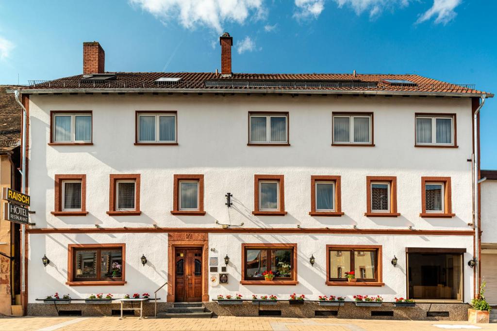 Hotel & Restaurant Raisch في Steinwenden: بيت ابيض شبابيكه على شارع