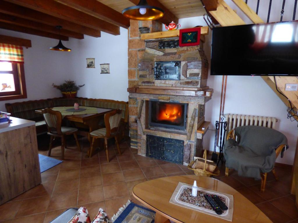 a living room with a fireplace and a table and a television at SVETLA U PLANINI in Bajina Bašta