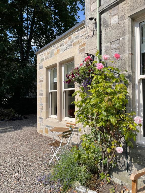 een gebouw met een raam en een bos met rozen bij Willows Apartment in Pitlochry