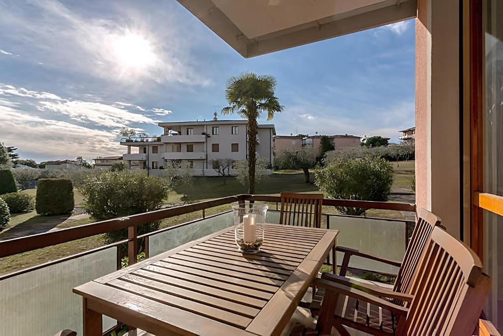 una mesa de madera en un balcón con vistas a una casa en Natural chic - Close to city center and beach - parking, en Desenzano del Garda