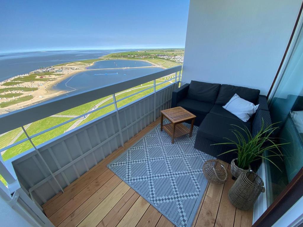 a balcony with a couch and a view of the ocean at Fewo Lotsenbude mit traumhaftem Blick über die Nordsee Etage 18 in Büsum