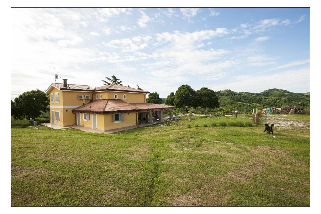 a house in a field with a cow in front of it at Bed & Breakfast Montesterlino in Cesena