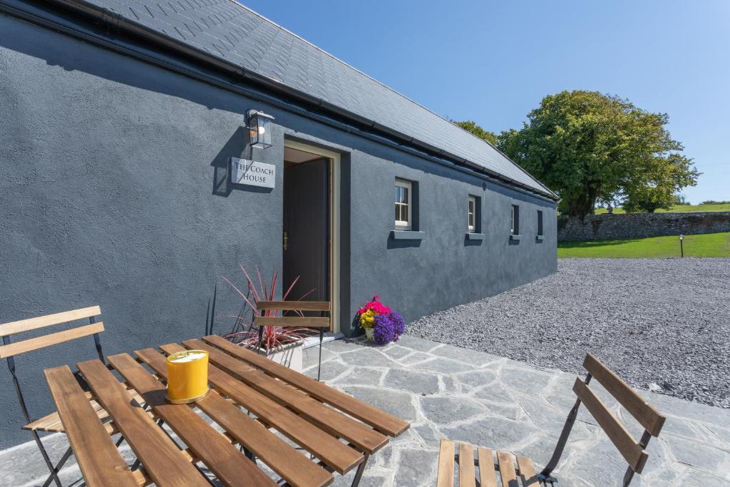 a patio with a bench and a building at Coach House Cottage on the shores of Lough Corrib in Galway