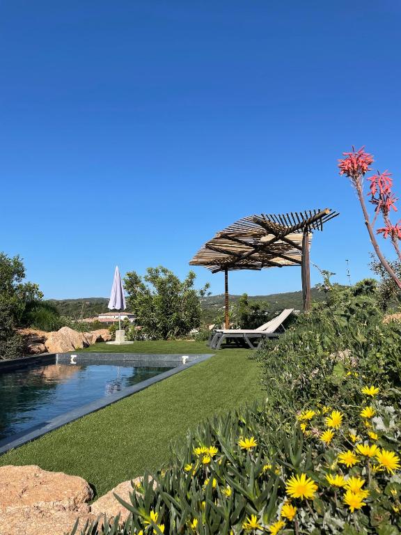 - une piscine avec un parasol et quelques fleurs dans l'établissement A Casa di Santa Giulia, à Porto-Vecchio