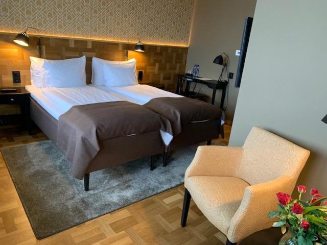 a bedroom with a large bed and a chair at Nybro Stora Hotellet in Nybro