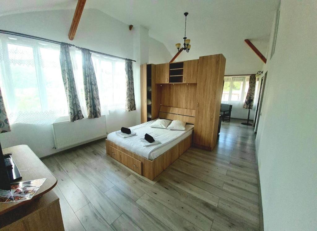 um quarto com uma cama num quarto com janelas em Casa Ostrov em Călimăneşti
