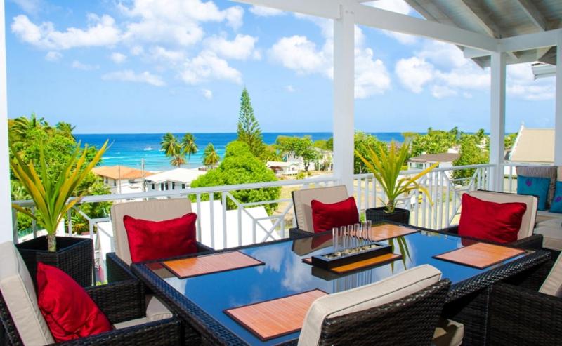 a patio with a table and chairs and the ocean at Lantana Resort Barbados by Island Villas in Saint James