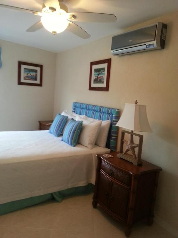 a bedroom with a bed and a fan and a lamp at Lantana Resort Barbados by Island Villas in Saint James