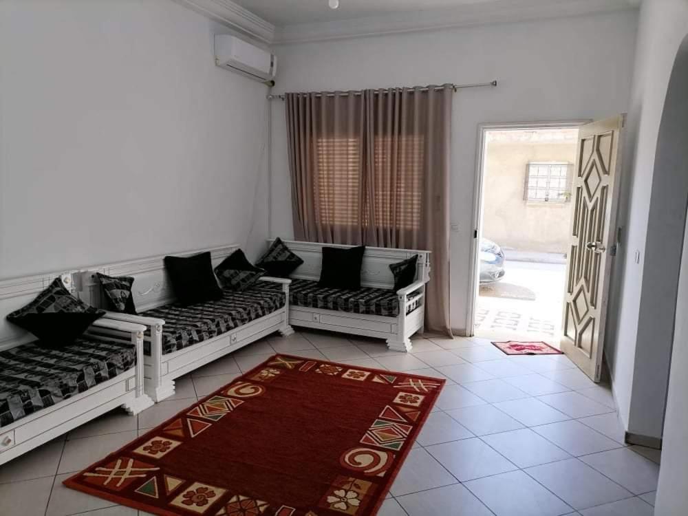 a living room with two white couches and a red rug at Maison a louer à kelibia in Kelibia