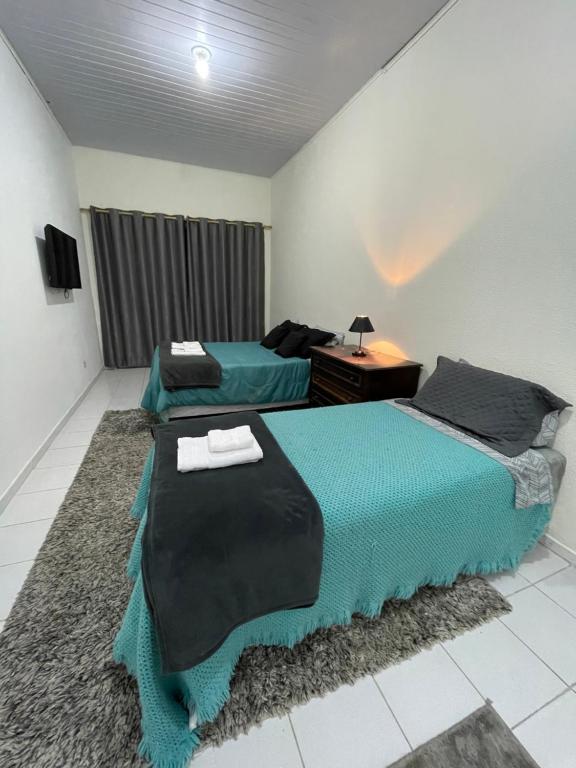 1 dormitorio con 2 camas, escritorio y TV en Kitnets da Lane, en Campos do Jordão
