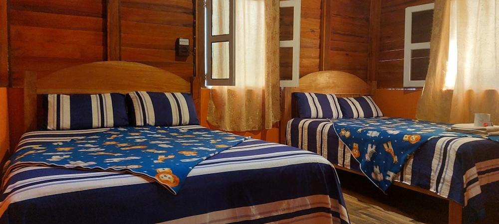 a bedroom with two beds with blue and white sheets at Cabañas Yax-ha in Arroyo Agua Azul
