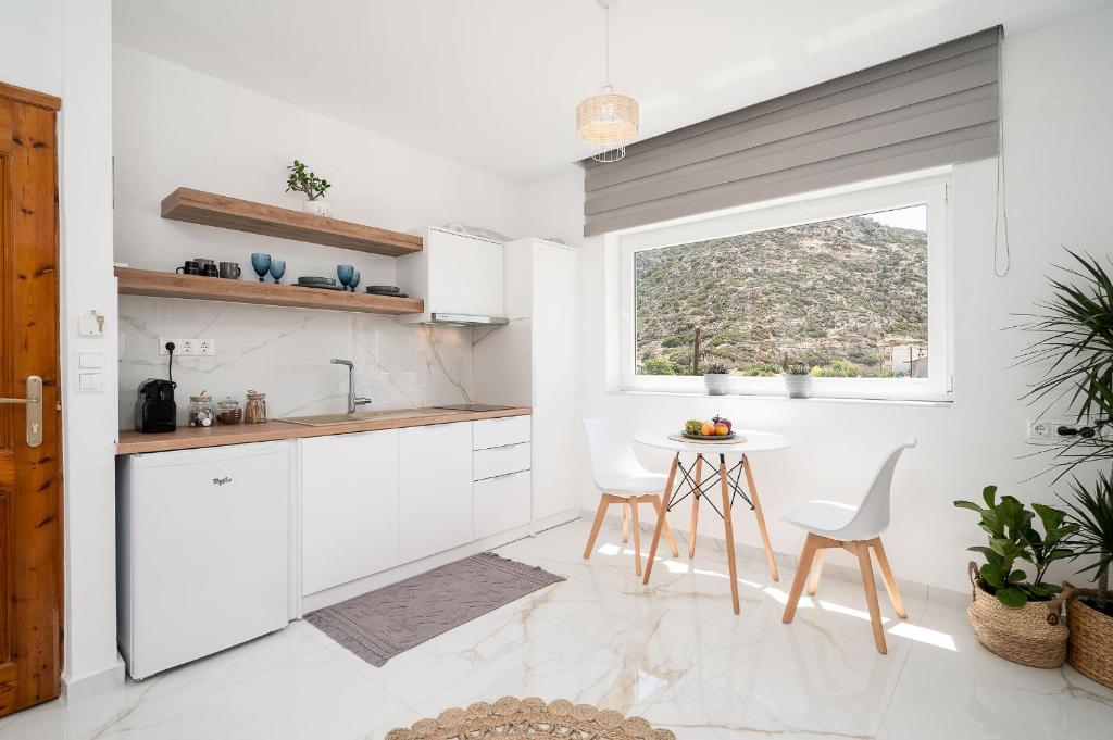 a kitchen with white cabinets and a table and a window at Amalia in Matala