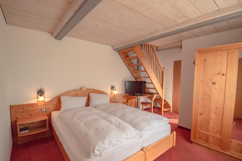 a bedroom with a bed and a wooden staircase at Hotel Eggishorn in Fiesch