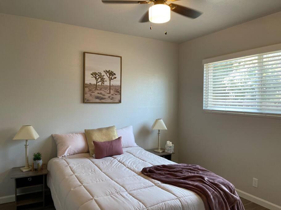 1 dormitorio con 1 cama blanca grande y ventilador de techo en Cathouse, en Visalia