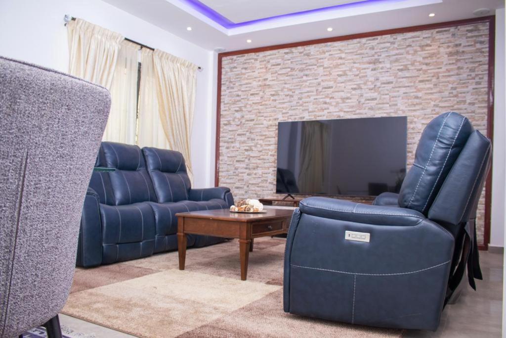 a living room with two blue chairs and a tv at luxury suites CHESTER ONE in Dakar