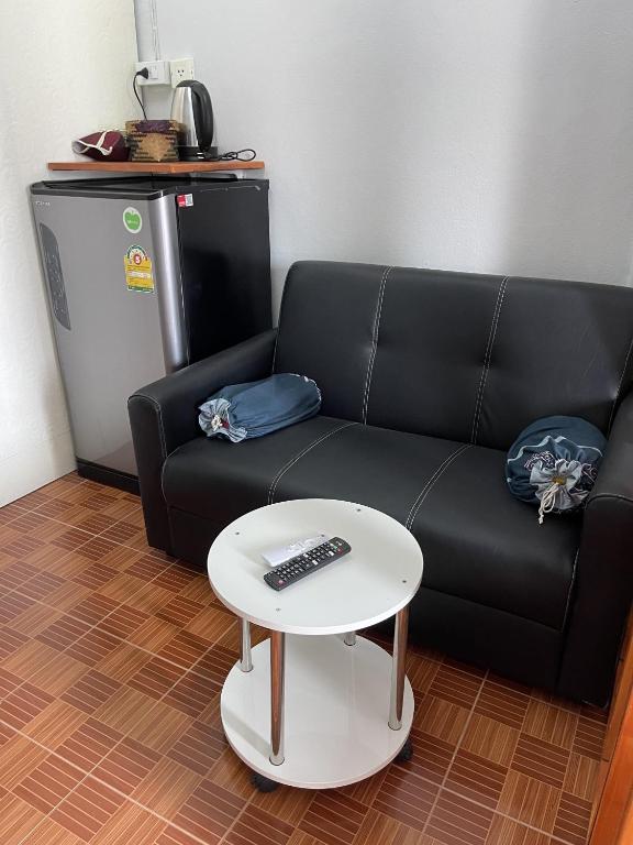 A black sofa and small round table form a compact sitting corner beside a minibar.