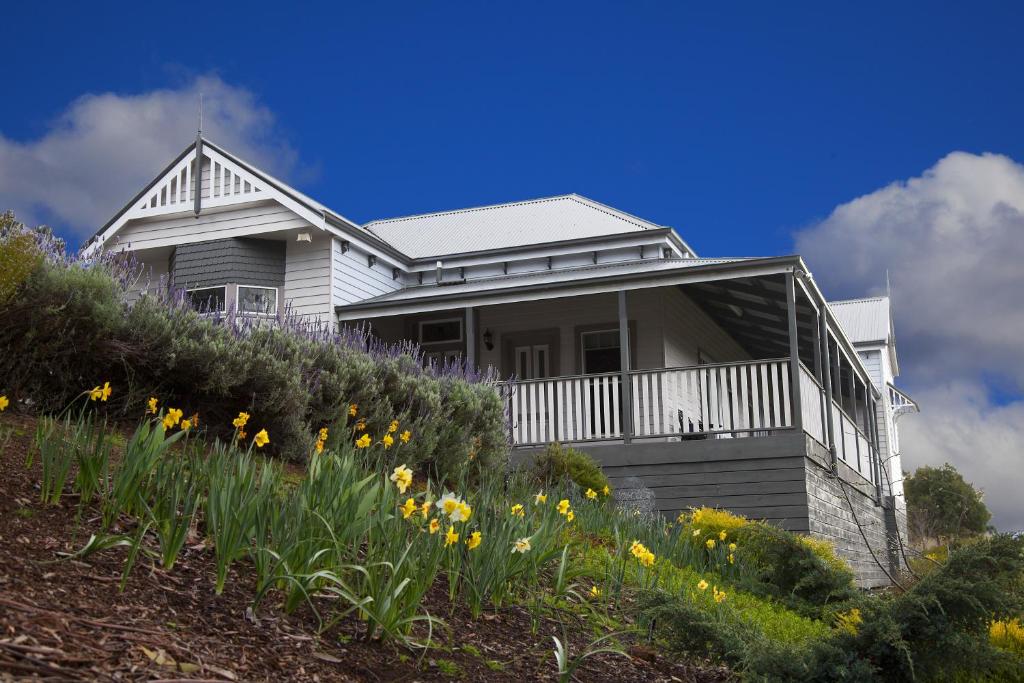 a white house on a hill with flowers at House on the Hill Bed and Breakfast in Huonville