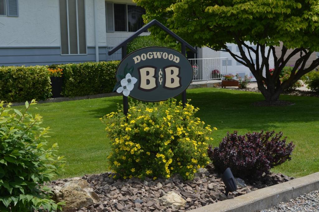 ein Schild in einem Garten mit Blumen im Hof in der Unterkunft Dogwood Bed & Breakfast in Summerland