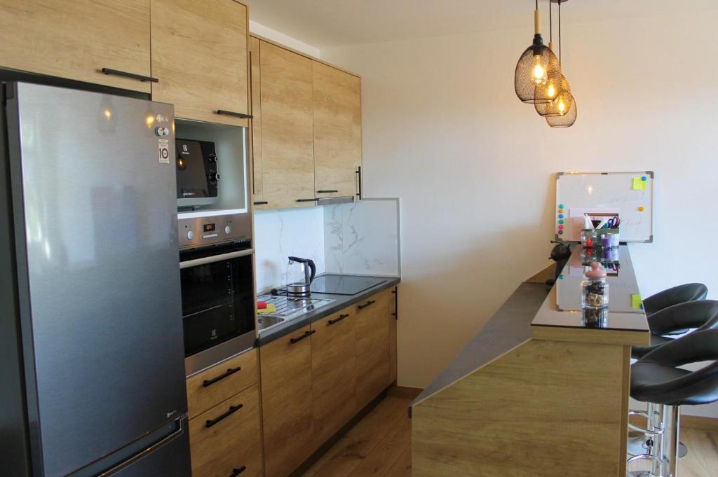 a kitchen with a stainless steel refrigerator and wooden cabinets at Apartman IM7 Međugorje in Međugorje