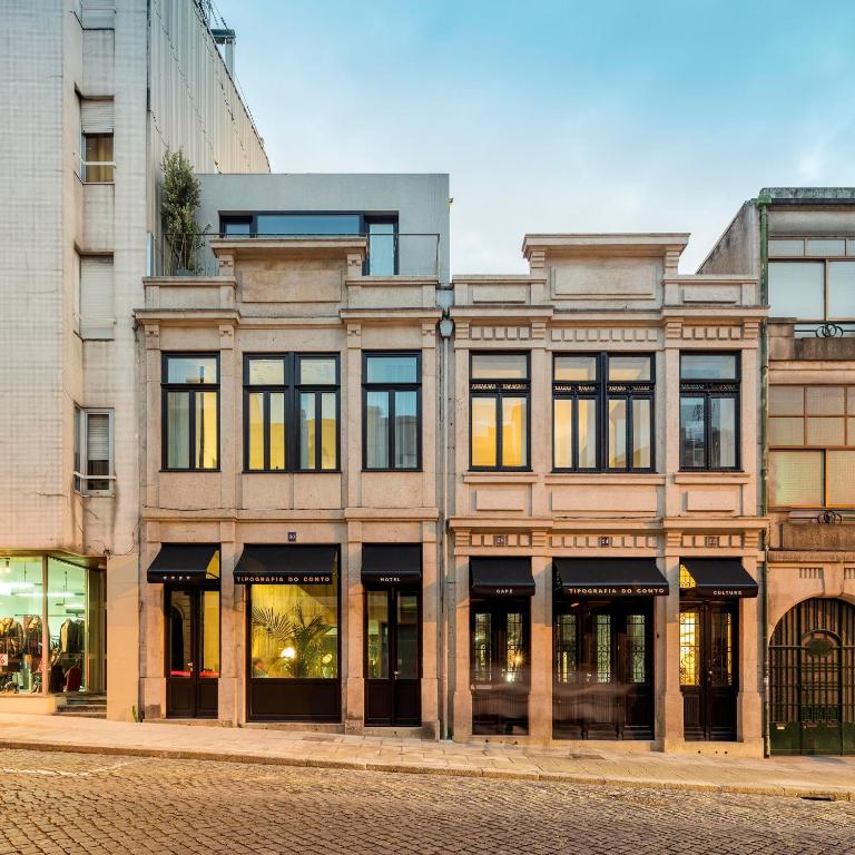 - un grand bâtiment avec des fenêtres donnant sur une rue de la ville dans l'établissement Hotel Tipografia do Conto by Casa do Conto, à Porto