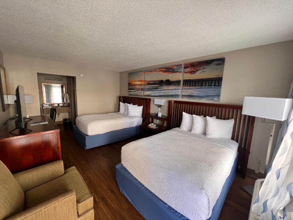 デイトナビーチにあるDays Inn by Wyndham Daytona Beach Speedwayのベッド2台とソファが備わるホテルルームです。