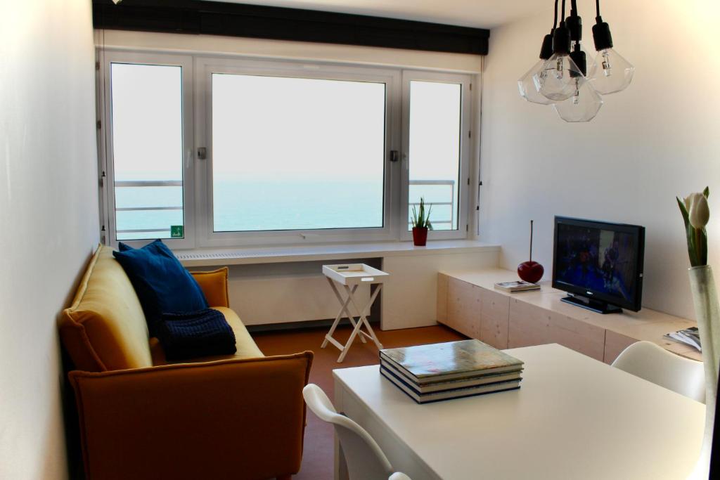 オーステンデにあるCompleet Appartement met Frontaal Zeezicht Oostendeのリビングルーム(テーブル、椅子、テレビ付)
