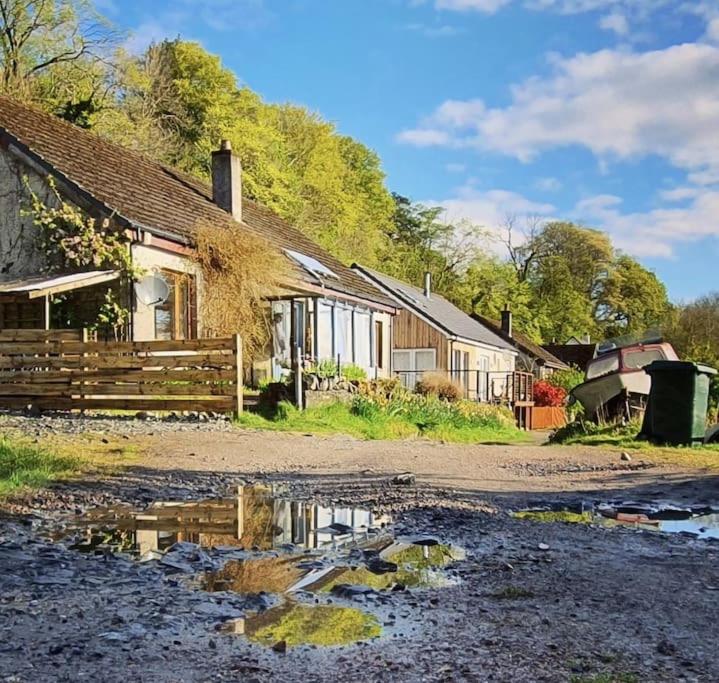 a house with a fence next to a dirt road at Tobar nan Iasgair Lismore in Achnacroish