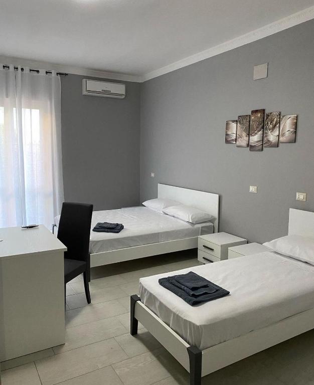 een slaapkamer met 2 bedden, een bureau en een stoel bij B&B Blu Krimisa in Cirò Marina