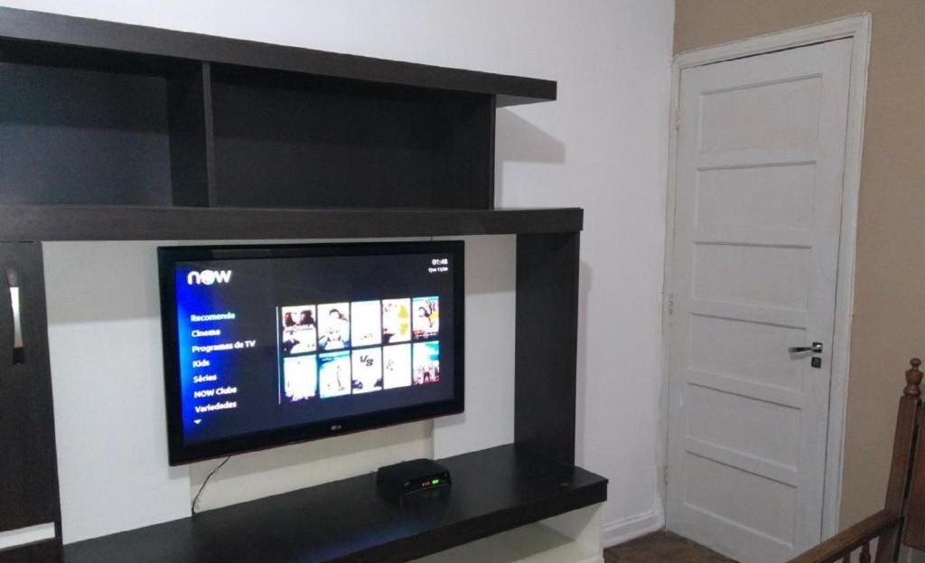 a flat screen tv sitting on a wall in a room at Apartamento Primeira Quadra Da Praia in Praia Grande