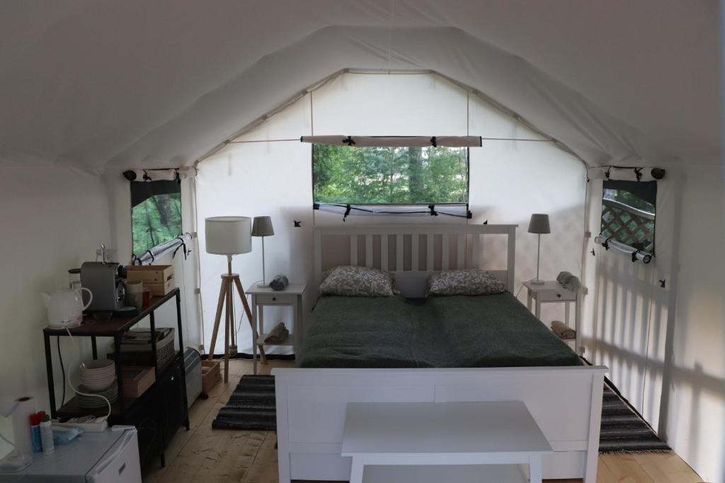 a bedroom with a bed in a white tent at Glempings Kaziņu ferma Līcīši in Ozolnieki