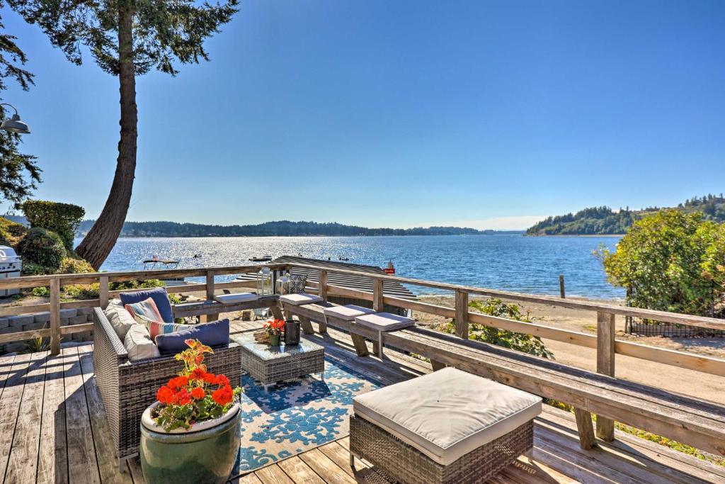 a wooden deck with a bench and a table with flowers at Gig Harbor House with Private Beach and Views! in Gig Harbor